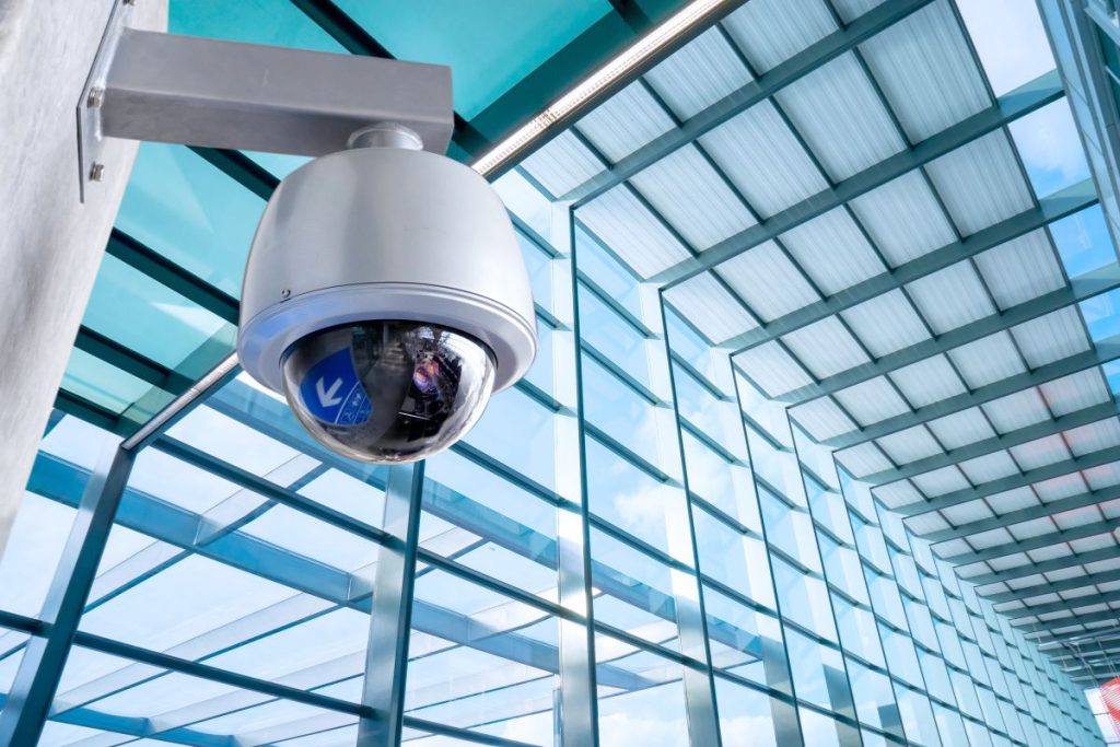A security camera mounted in front of a building, labeled as "Best Security Camera."