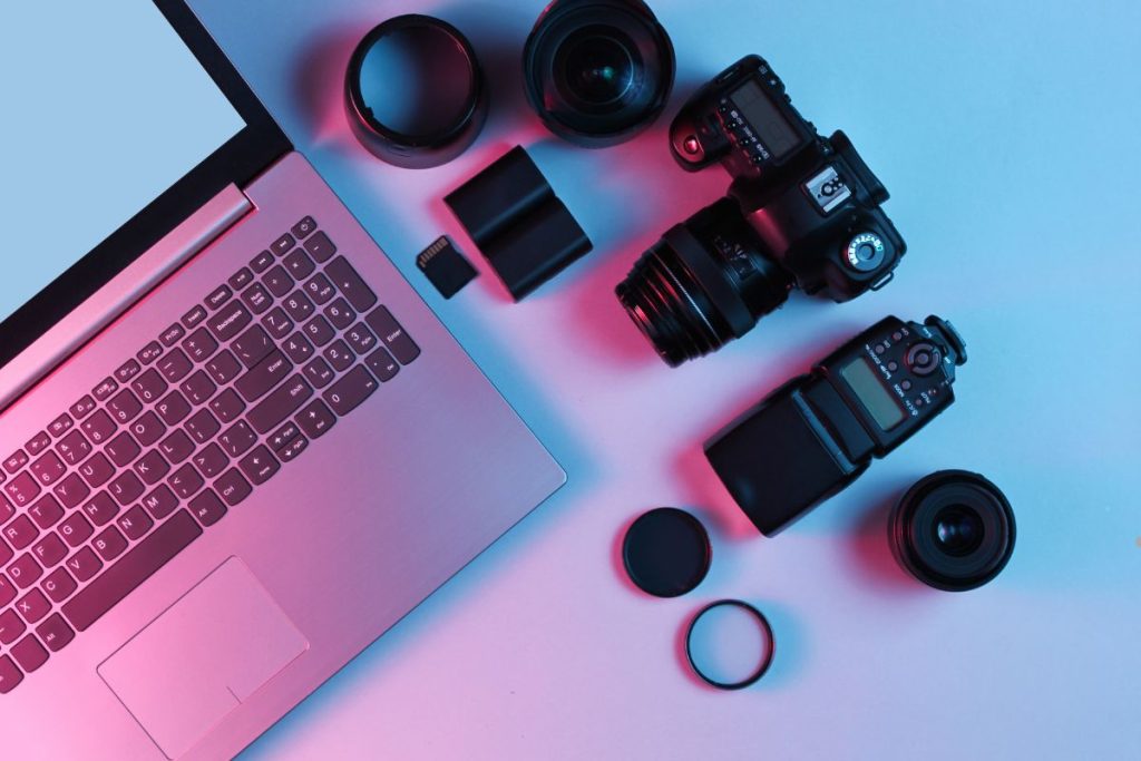 A laptop, camera, and various accessories arranged neatly on a table, emphasizing high-quality camera equipment.